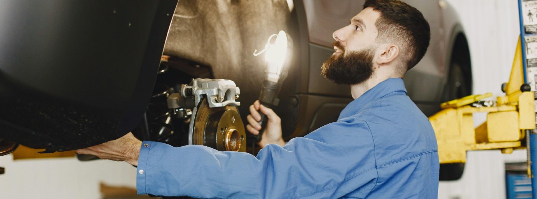 A stock photo of a person working on a set of brakes.