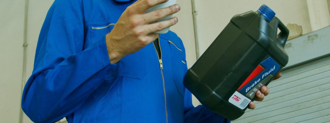 A stock photo of a person holding a bottle of brake fluid.