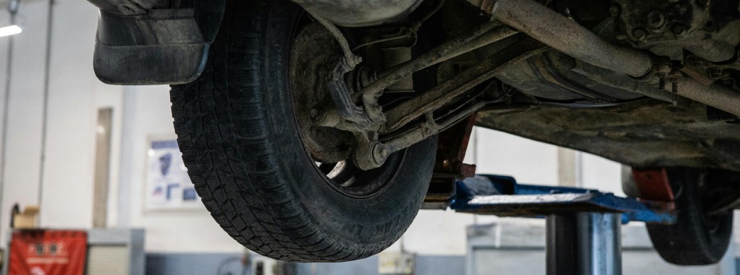 A stock photo of a car on a lift getting its tires changed.