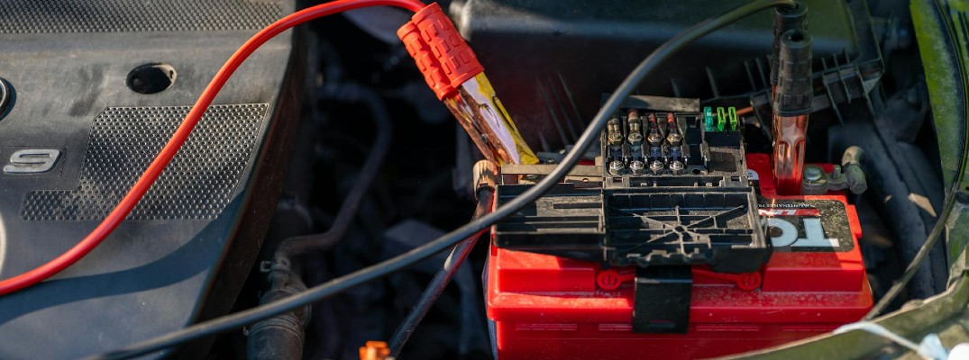A stock photo of a car's battery with jumper cables attached.